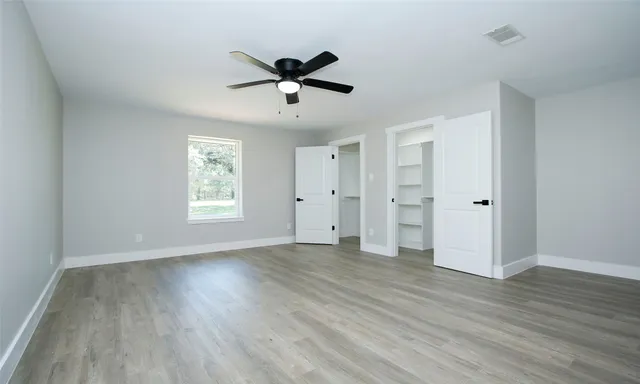 a view of empty room with wooden floor and ceiling fan