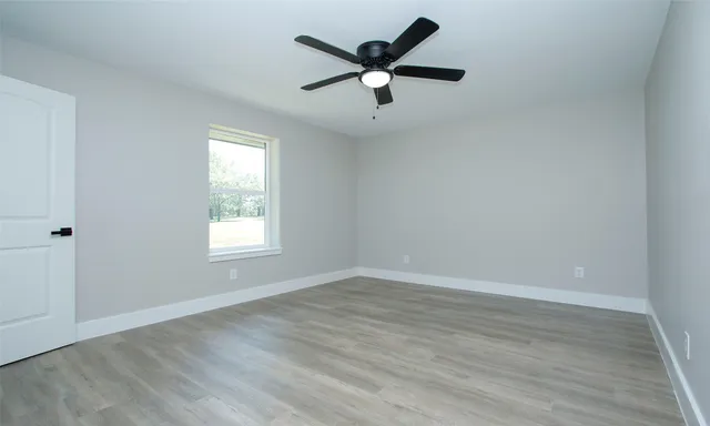 an empty room with wooden floor and windows