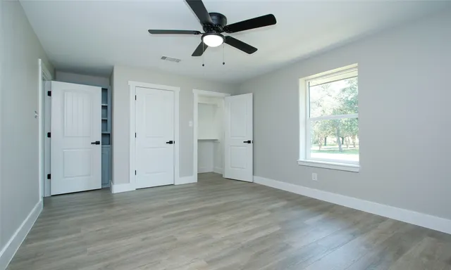 a view of an empty room with wooden floor and a window