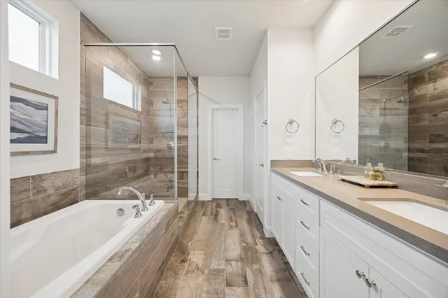 a bathroom with a granite countertop tub sink shower and mirror
