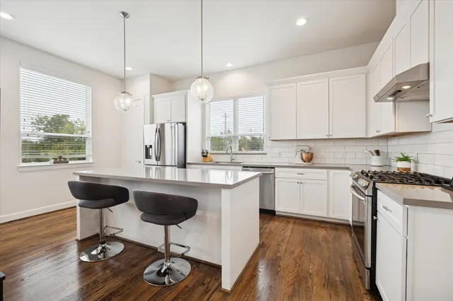 a kitchen with stainless steel appliances granite countertop a sink a stove a refrigerator cabinets and chairs