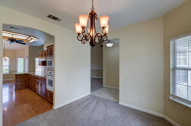 an empty room with windows fireplace and a chandelier fan