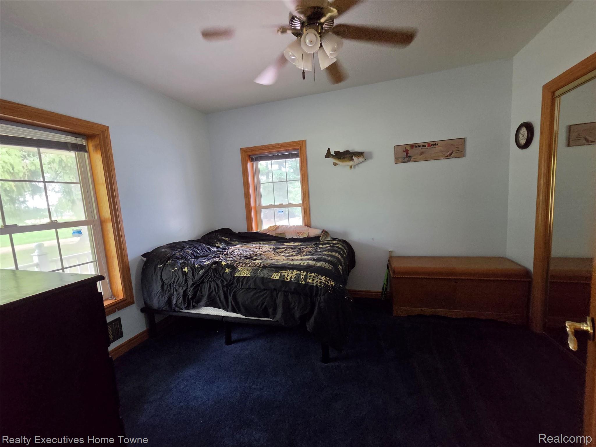 2715 Cash Road Applegate, MI 48401 - Photo 22 of 59 Lower level bedroom featuring two windows with wood trim, a ceiling fan with light fixture, and blue carpeting