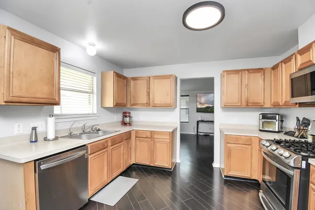 a kitchen with stainless steel appliances granite countertop a stove a sink dishwasher and a microwave oven with cabinets