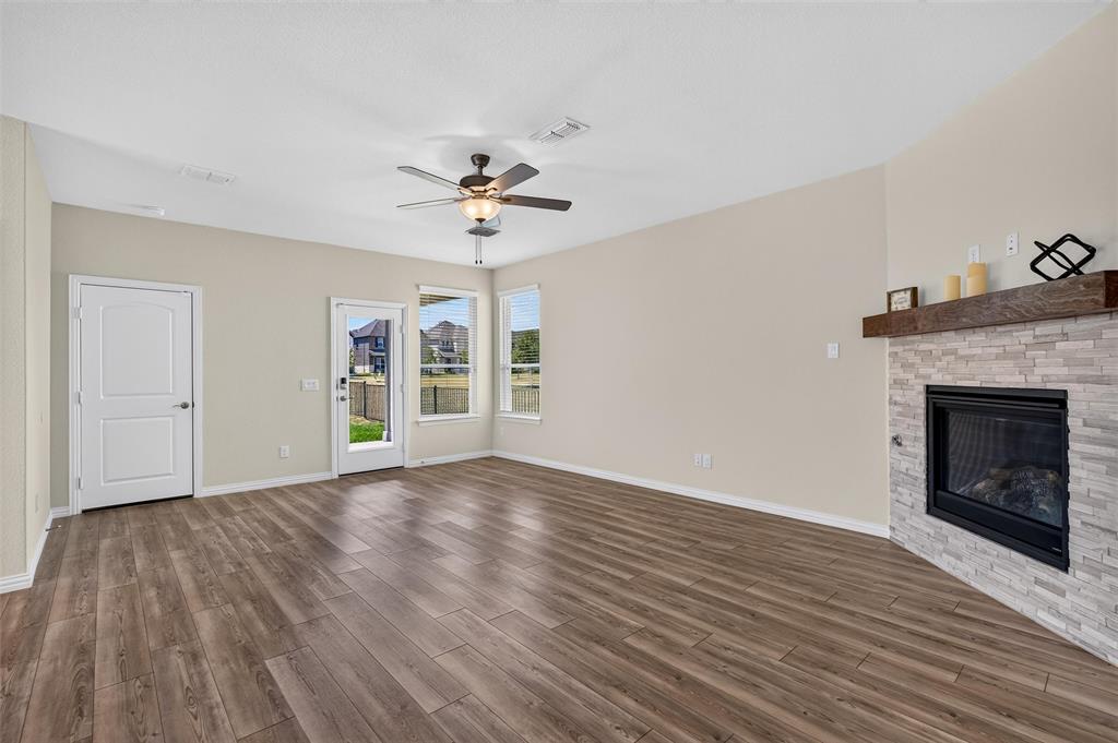 8715 Royal Star Road Rowlett, TX 75089 - Photo 11 of 39 Wood-finish flooring, ceiling fan, fireplace with stone surround, wood mantel, and multiple windows