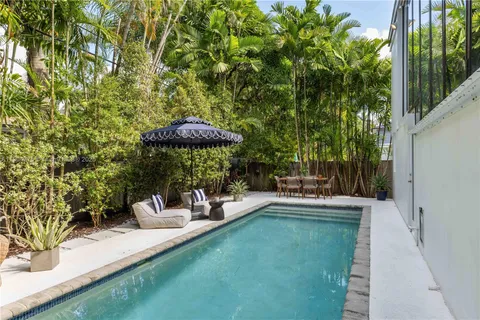a view of a patio with couches table and chairs under an umbrella with a small yard