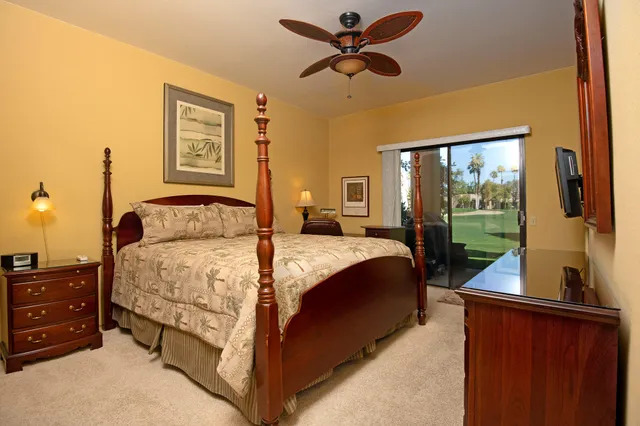 a bedroom with a bed and a flat tv screen on dresser