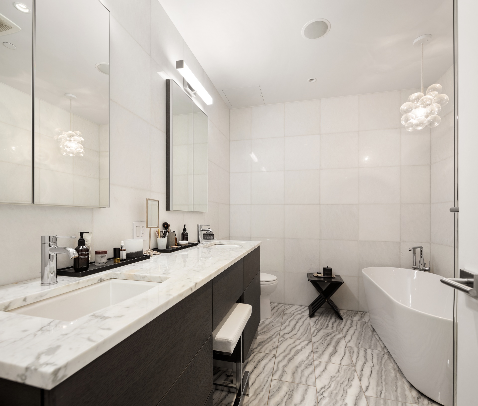 121 Mercer Street, Unit 4 Manhattan, NY 10012 - Photo 10 of 14 a bathroom with a double vanity sink a mirror and a bathtub