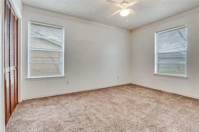 an empty room with windows and fan