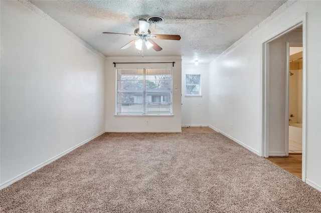 an empty room with windows and chandelier fan