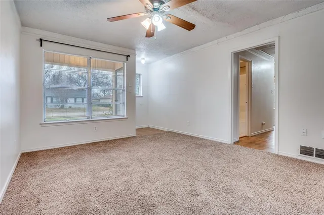 an empty room with chandelier fan and windows