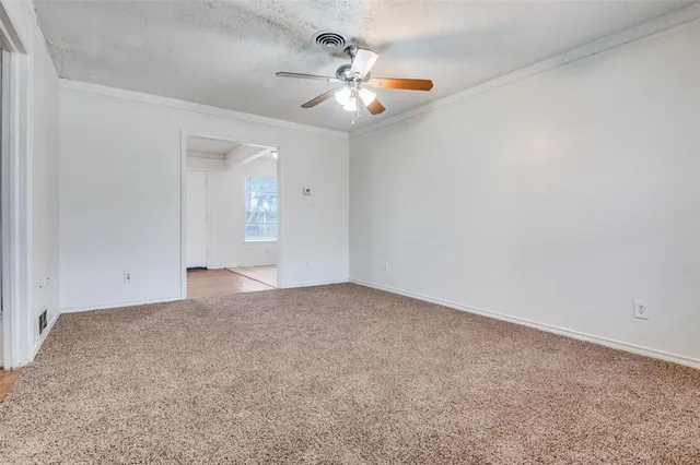 an empty room with chandelier fan and windows