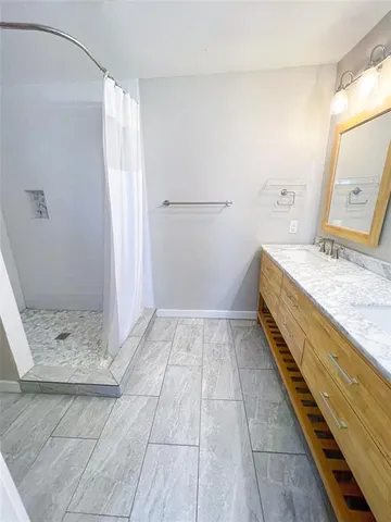 a bathroom with a granite countertop sink a mirror and shower