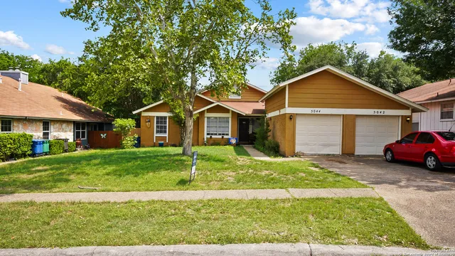 a front view of a house with a garden and trees