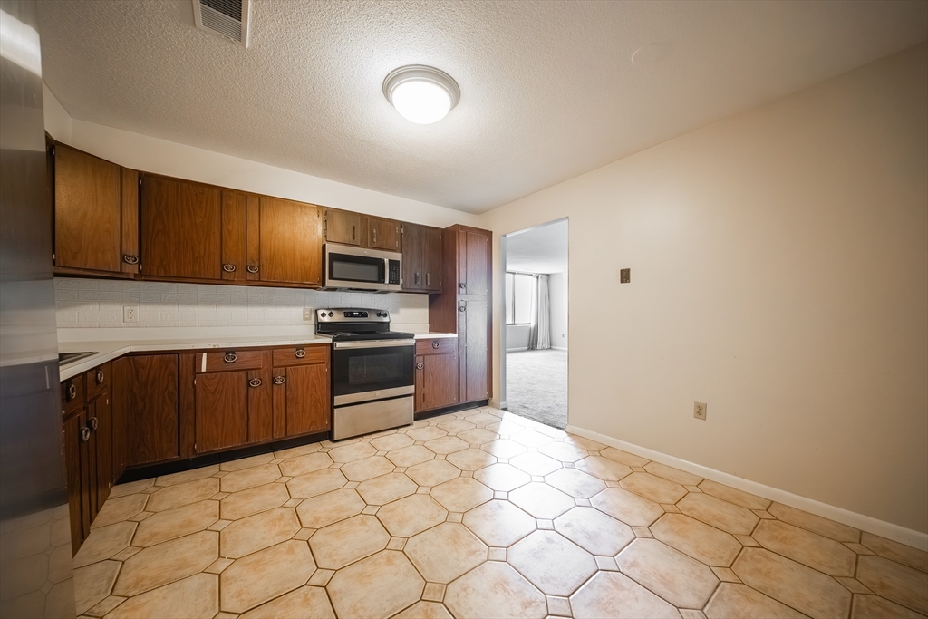 1002 Paradise Road, Unit PHE Swampscott, MA 01907 - Photo 3 of 23 a kitchen with granite countertop a refrigerator and a stove top oven