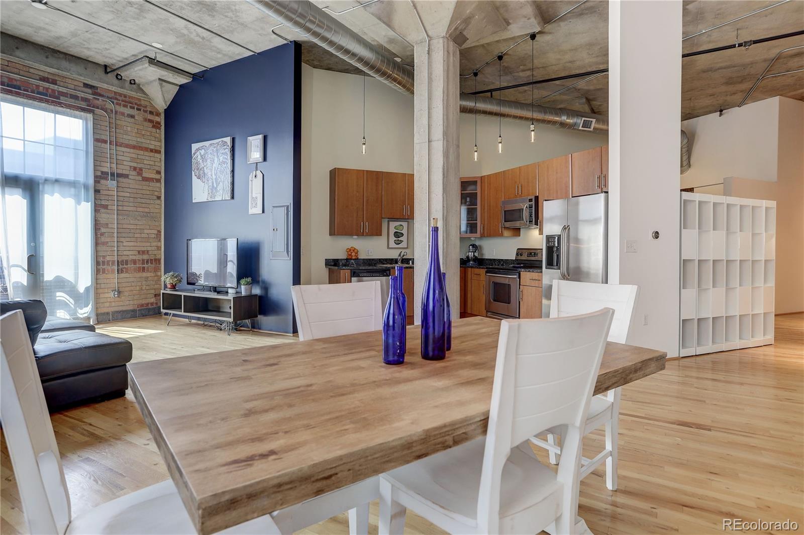 2500 Walnut Street, Unit 212 Denver, CO 80205 - Photo 24 of 39 a kitchen with stainless steel appliances wooden floor dining table and chairs