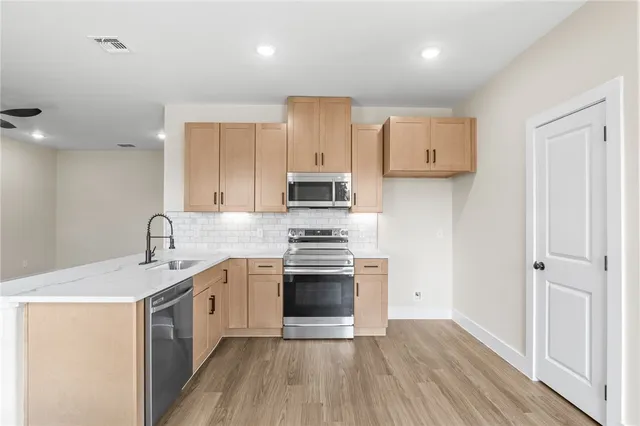 a view of a hallway with wooden floor and a bathroom
