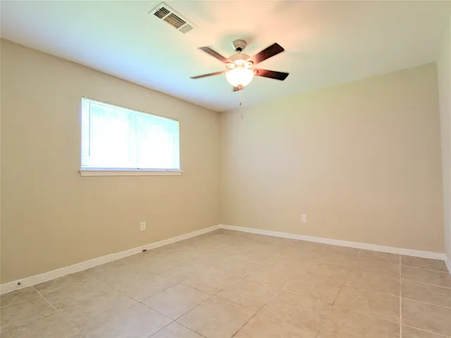 an empty room with windows and fan