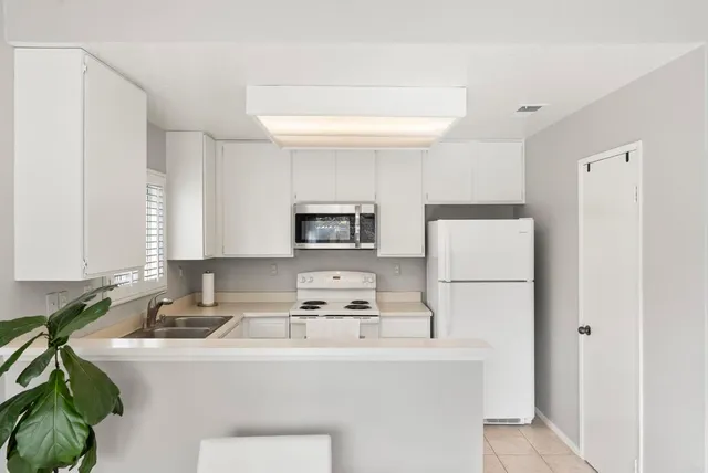 a kitchen with stainless steel appliances a refrigerator sink and white cabinets