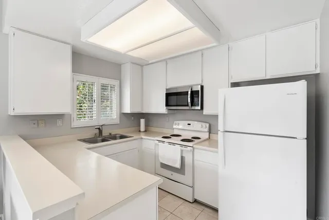 a kitchen with cabinets appliances a sink and a window
