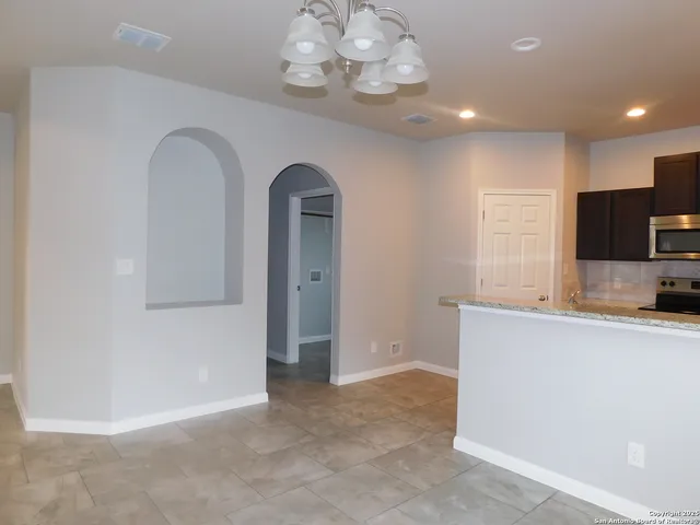 a view of kitchen with stainless steel appliances granite countertop cabinets and chandelier