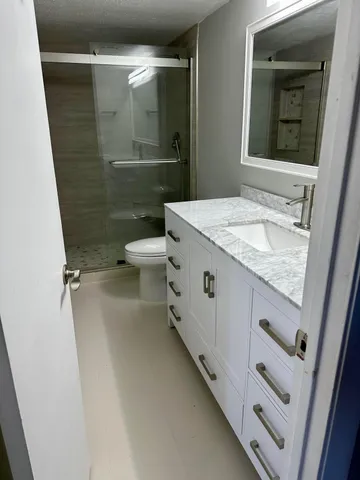 a bathroom with a granite countertop sink toilet and shower