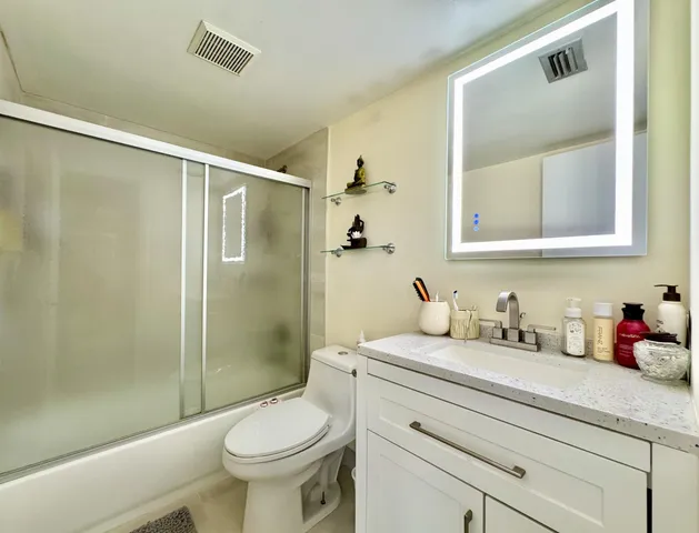 a bathroom with a granite countertop sink toilet and shower