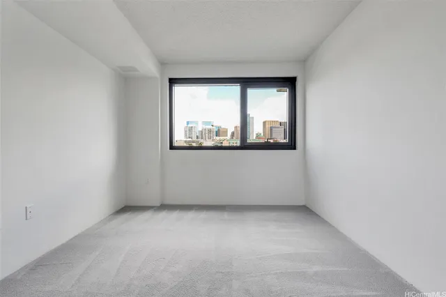 a view of an empty room with wooden floor and a bathroom