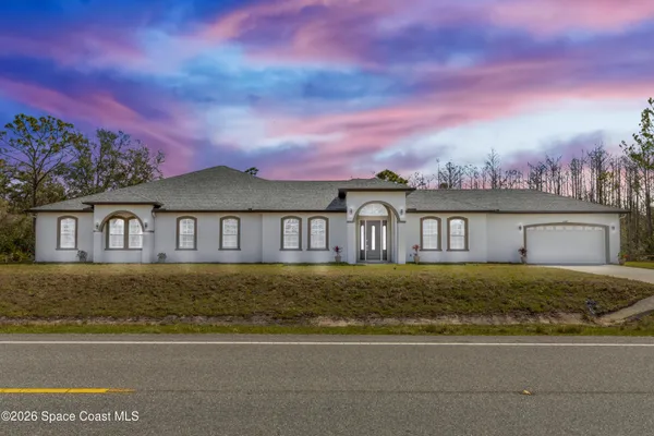 a view of a big house with a big yard and large trees