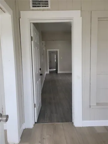 a view of a hallway with wooden floor and a livingroom