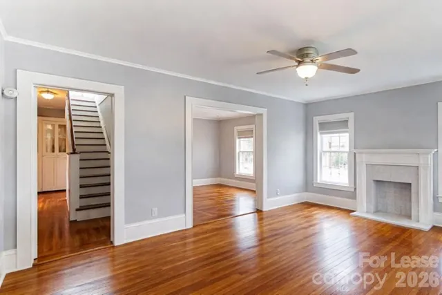 a view of an empty room with a window and wooden floor