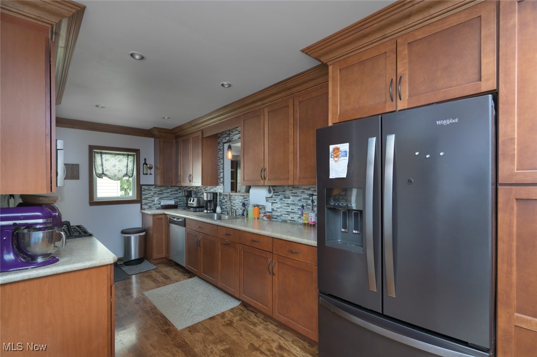 3234 Bell Wick Road Hubbard, OH 44425 - Photo 17 of 27 Kitchen with refrigerator with ice dispenser, brown cabinets, dark wood finished floors, decorative backsplash, and crown molding