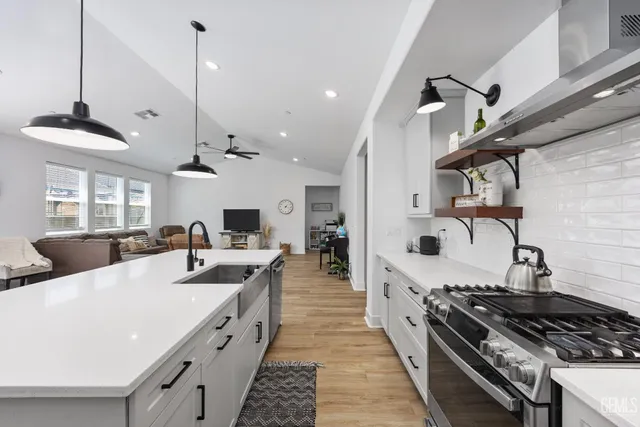 a large kitchen with stainless steel appliances a stove a sink dishwasher and a dining table with white cabinets