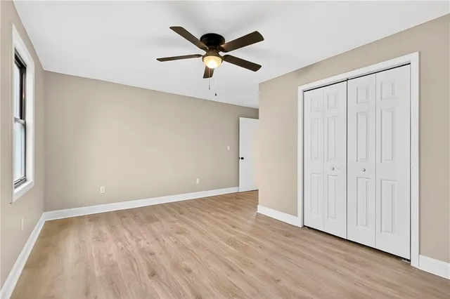 an empty room with wooden floor and a ceiling fan