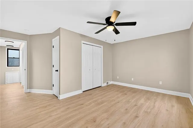 an empty room with wooden floor ceiling fan and windows