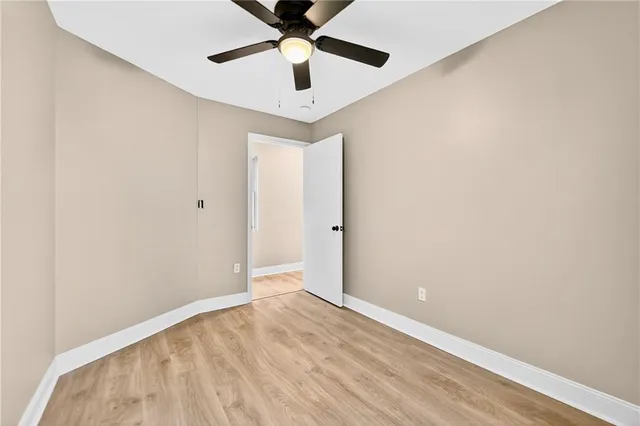 an empty room with a ceiling fan and wooden floor