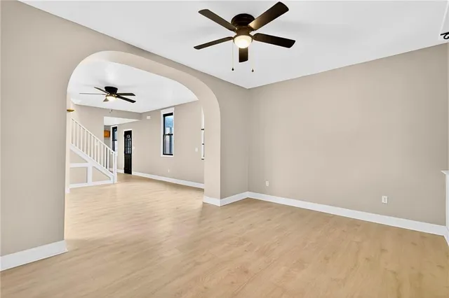 an empty room with a ceiling fan and wooden floor
