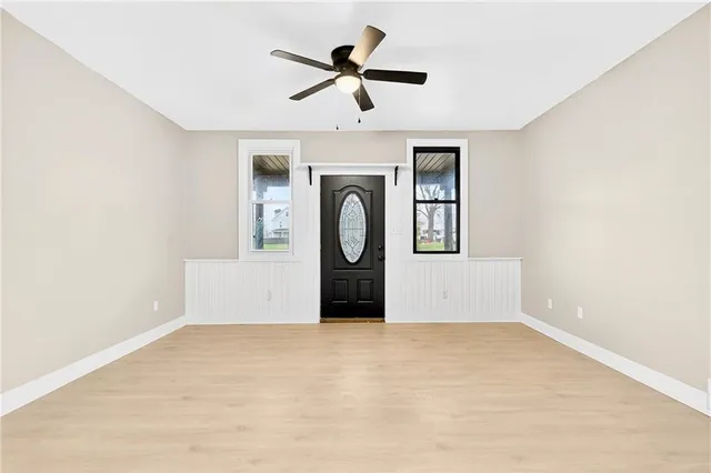 an empty room with ceiling fan and windows