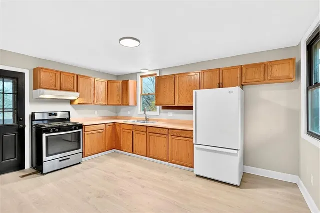 a kitchen with granite countertop a refrigerator stove top oven a sink and dishwasher