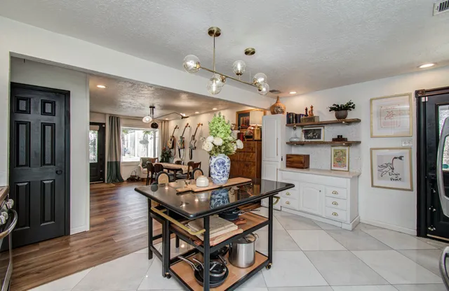 a kitchen with stainless steel appliances kitchen island granite countertop a refrigerator a stove and white cabinets with wooden floor