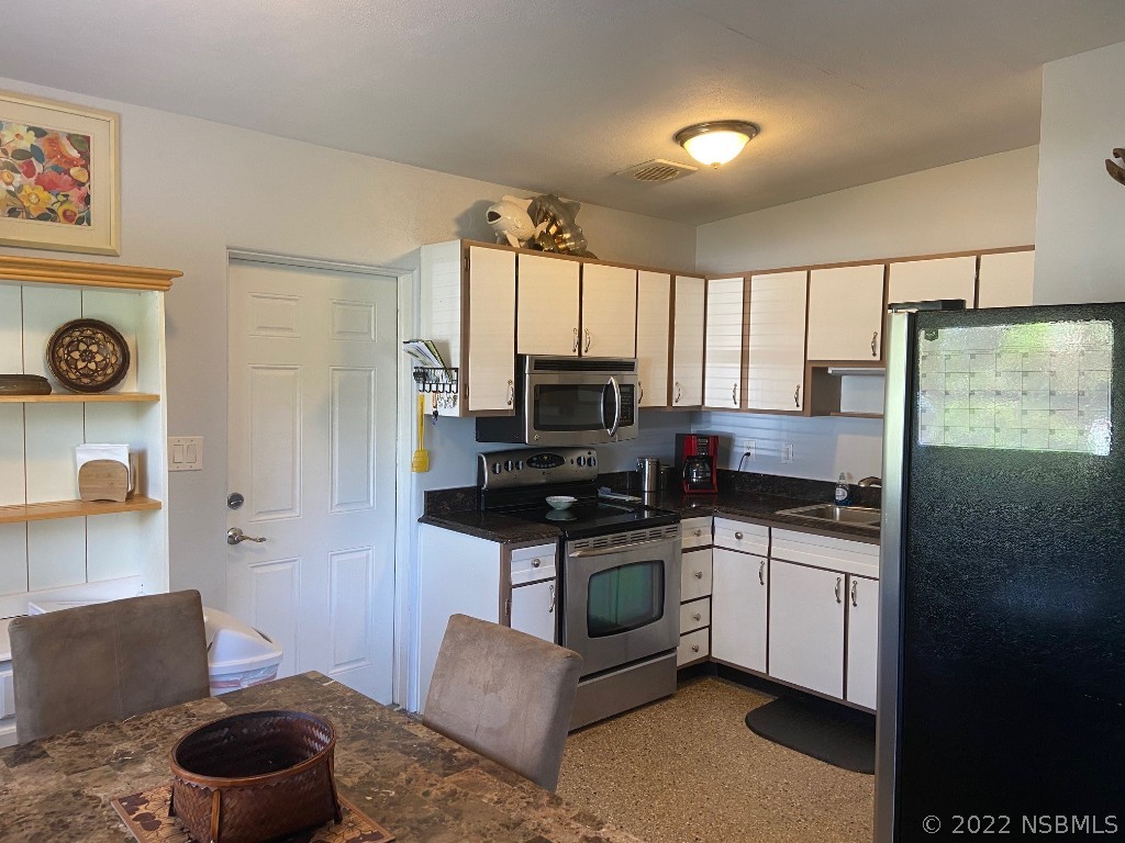 229 Robinson Road New Smyrna Beach, FL 32169 - Photo 7 of 23 a kitchen with stainless steel appliances granite countertop a stove a sink and a refrigerator