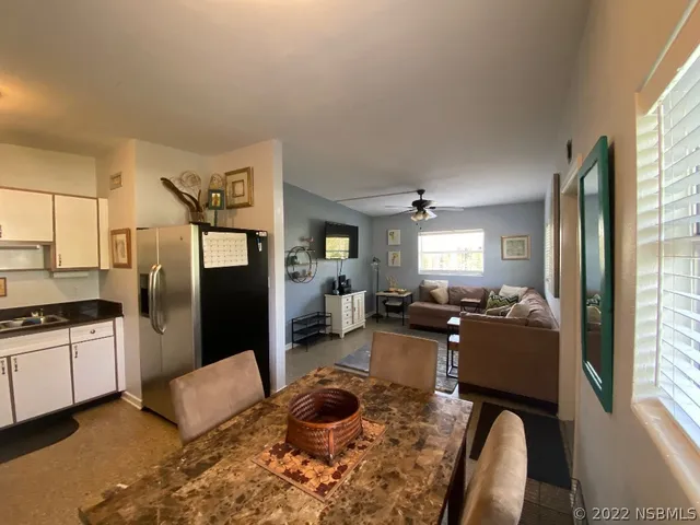 a living room with stainless steel appliances furniture a rug a fireplace and a window