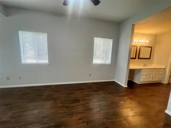 an empty room with wooden floor and windows