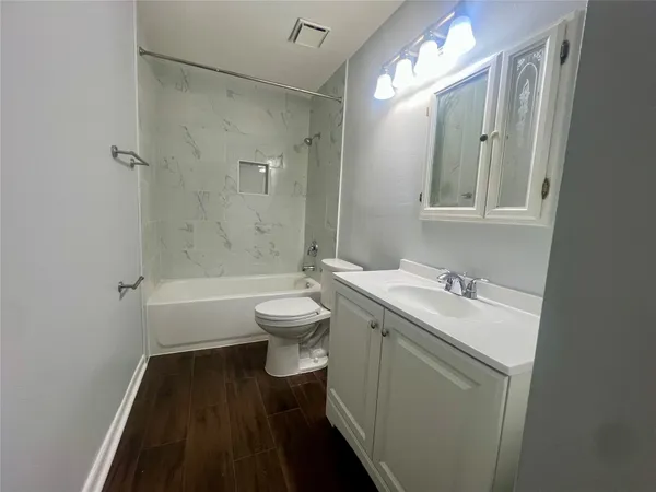 a bathroom with a granite countertop sink toilet a mirror and a bathtub