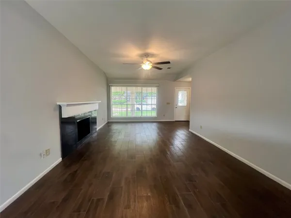 an empty room with wooden floor fireplace and windows