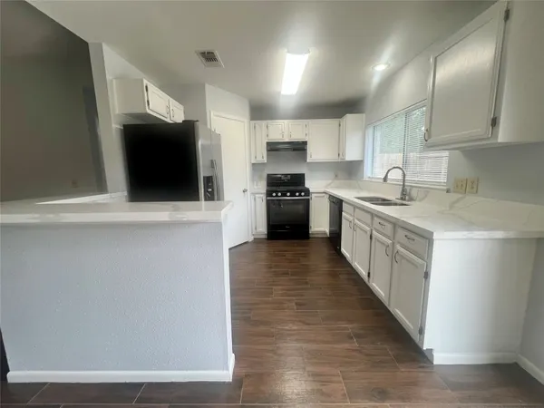 a kitchen with stainless steel appliances granite countertop a sink a stove top oven a counter space and cabinets