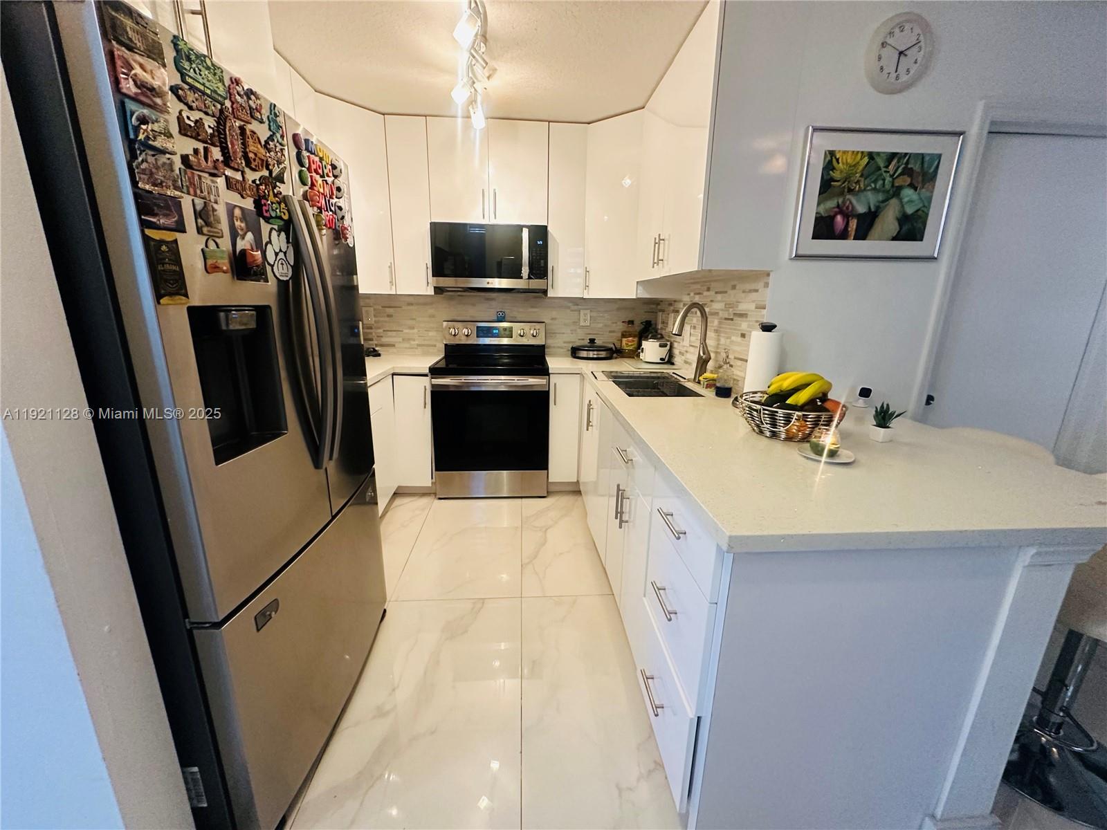 14343 Southwest 10th Street, Unit 2305 Pembroke Pines, FL 33027 - Photo 12 of 29 a kitchen with stainless steel appliances a refrigerator a sink a stove a microwave oven a sink and dishwasher