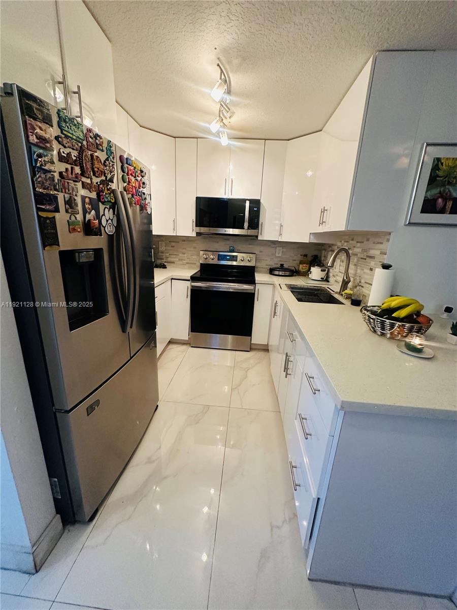 14343 Southwest 10th Street, Unit 2305 Pembroke Pines, FL 33027 - Photo 13 of 29 a kitchen with stainless steel appliances a stove microwave and a refrigerator