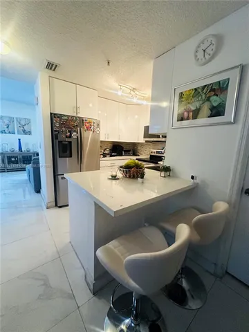 a kitchen with a dining table chairs and refrigerator