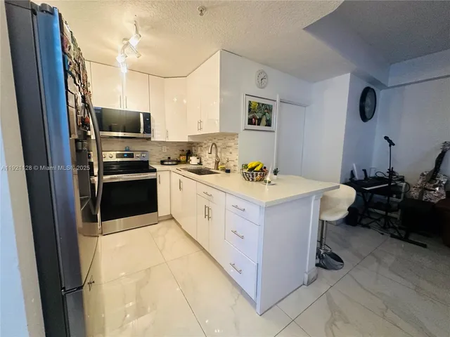 a kitchen with stainless steel appliances a sink stove refrigerator and cabinets